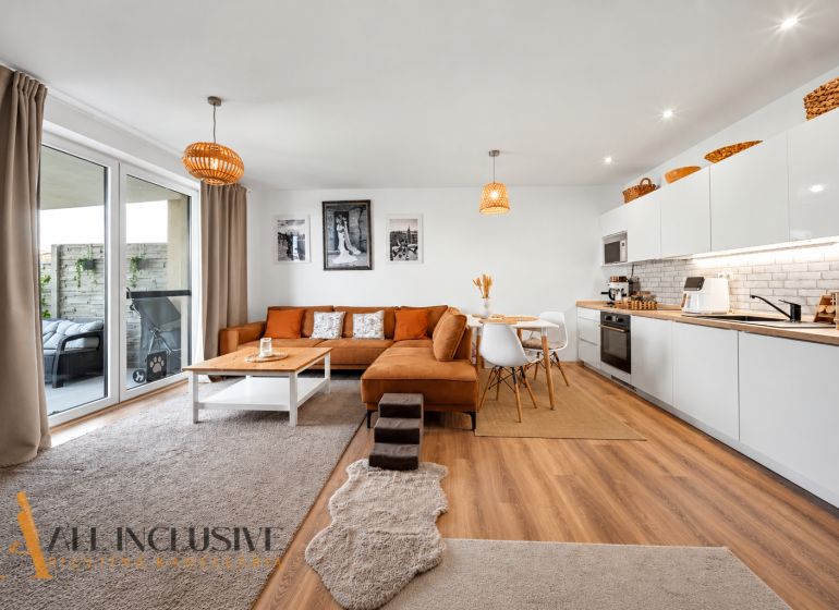 Interior of a family house with a bright kitchen, orange sofa, and a floor with a wooden decor.