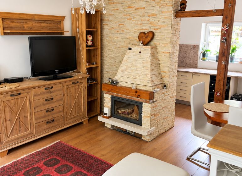 Living room with a fireplace, wood-patterned floor, carpet, chandelier, and wooden furniture.