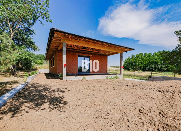 A family house in Čeľadice with an unfinished garden, surrounded by greenery and a blue sky.