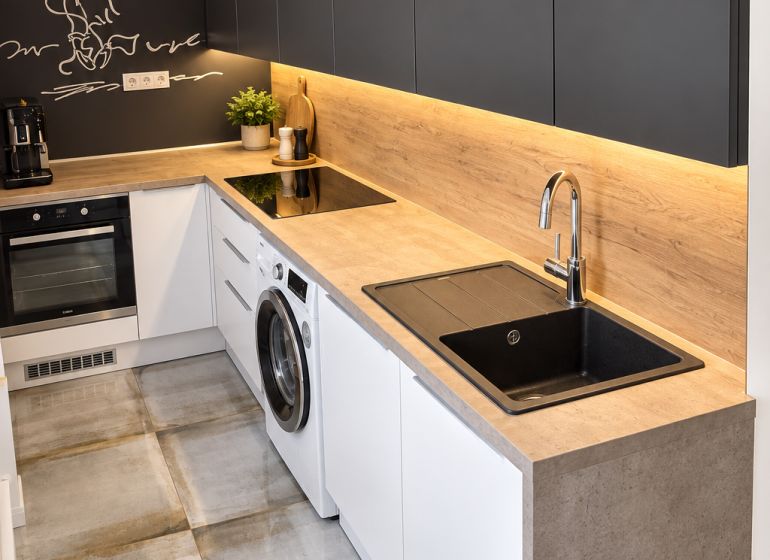 A kitchen with appliances and a wooden decor floor in a 3-room apartment.