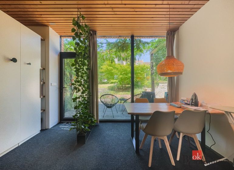 Dining area in a 3-room apartment with large windows and a garden.