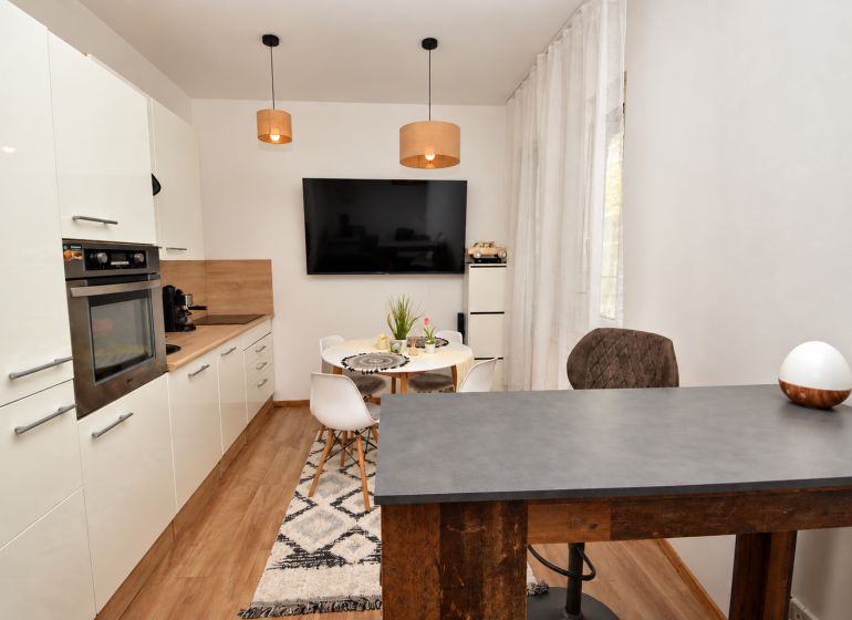 A kitchen in a studio apartment with a wood-patterned floor and a dining table.