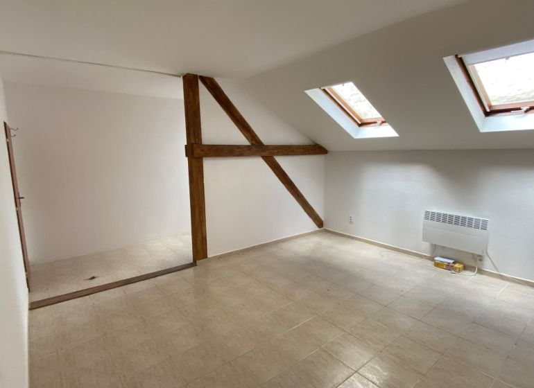 Attic office with ceramic floor and skylights, wooden beam.