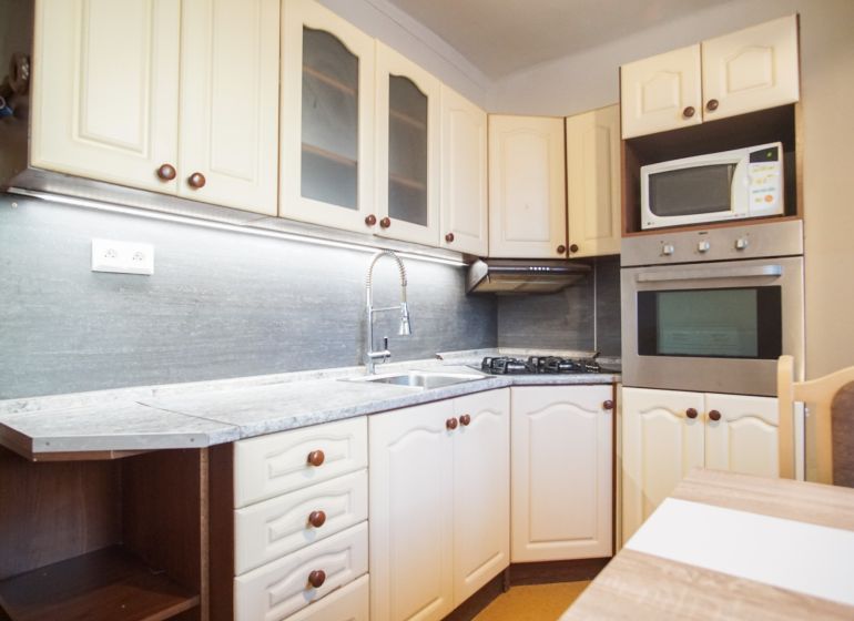 A kitchen in a 2-room apartment with white cabinets and built-in appliances.