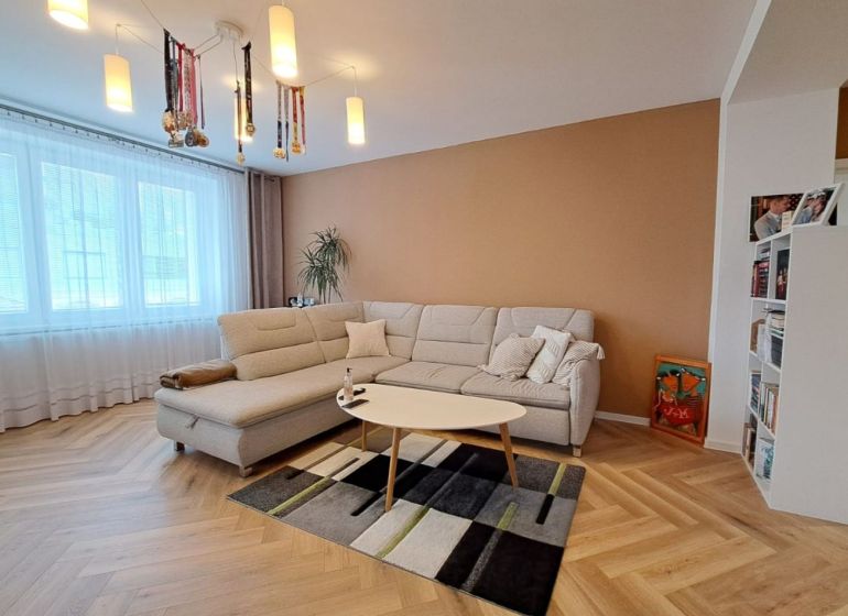 Living room in a 3-room apartment with a white sofa and a floor with a wood decor.