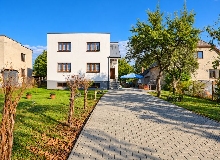 A family house in Martin with a driveway and a garden, surrounded by greenery and trees.