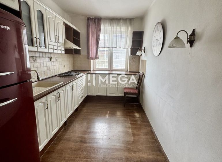 A kitchen in a 3-room apartment with a wooden decor floor, white furniture, red refrigerator.