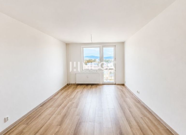 A spacious living room with access to a balcony and a floor with a wooden decor in a 2-room apartment.