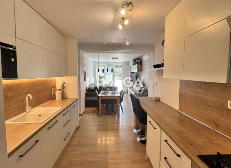 A kitchen in a 3-room apartment with a wood-decor floor and white cabinets.
