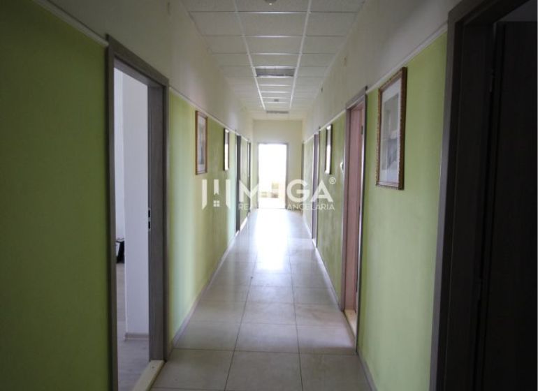 A hallway in offices with pale walls and light tiled flooring.