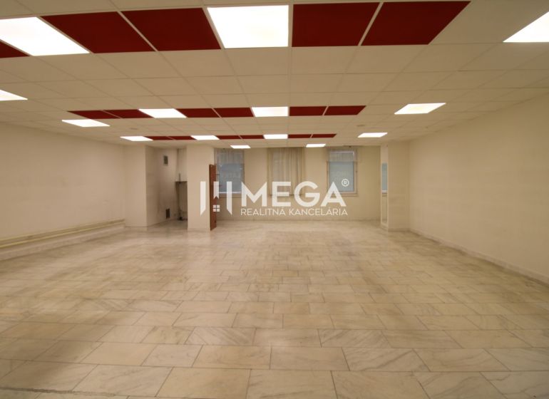 Spacious commercial spaces with tiled floors and a bright ceiling with red panels.