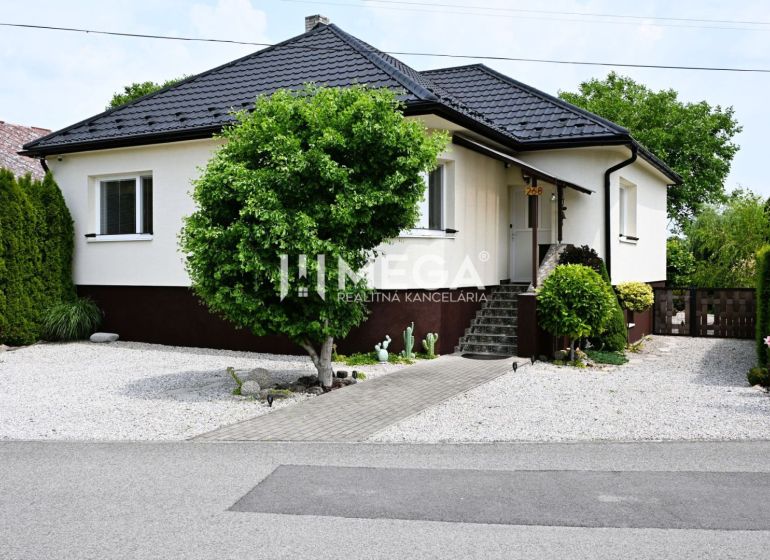 A family house in Udavské with a landscaped garden, a walkway, and ornamental shrubs.