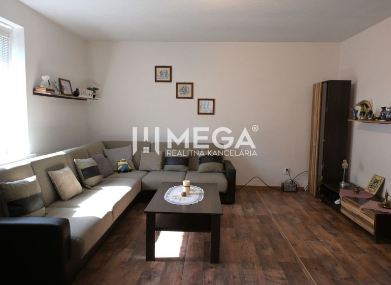 Living room with a sofa, table, and wooden decor flooring in a family house.