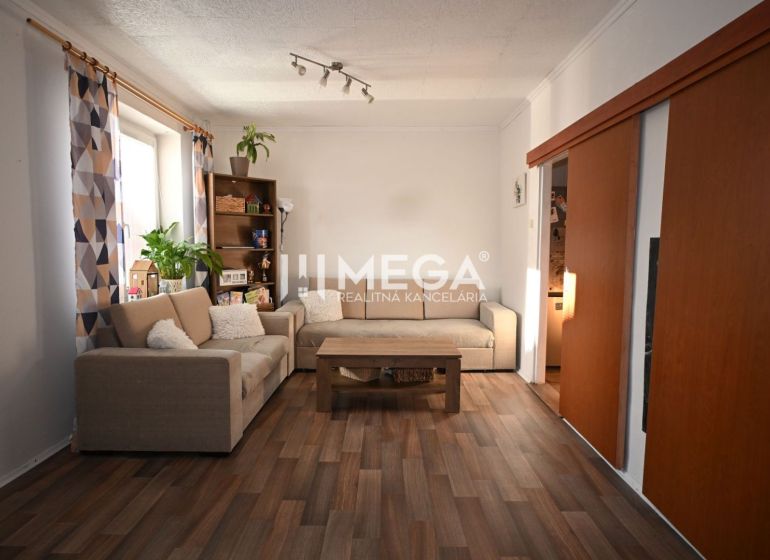 Living room in a two-room apartment with a wooden decor floor and a comfortable sofa set.