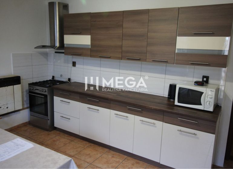 A kitchen in a family house with a wooden decor, a cooktop, a microwave, a fan.