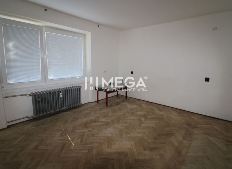 A room with a wooden decor floor and a radiator in a 2-room apartment.
