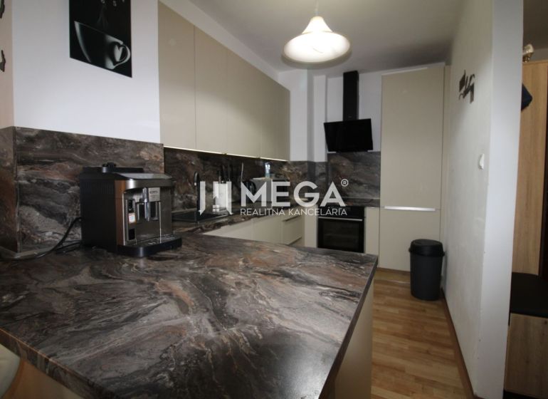 A kitchen in a 2-room apartment with a dark marble decor and a wooden decor floor.