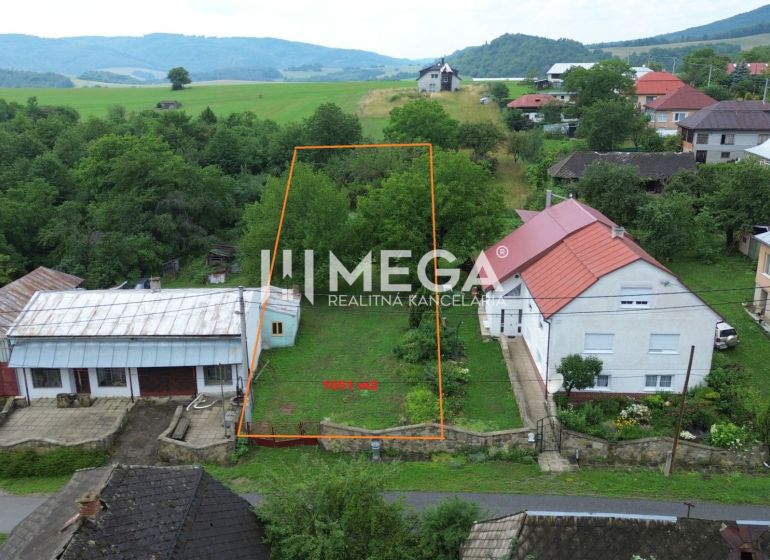 A plot of land in Oľšinkov suitable for living, surrounded by greenery and nearby houses.