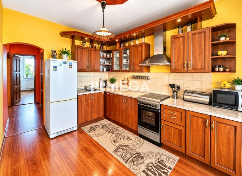 A kitchen with yellow walls, a wooden decor floor in a 4-room apartment.