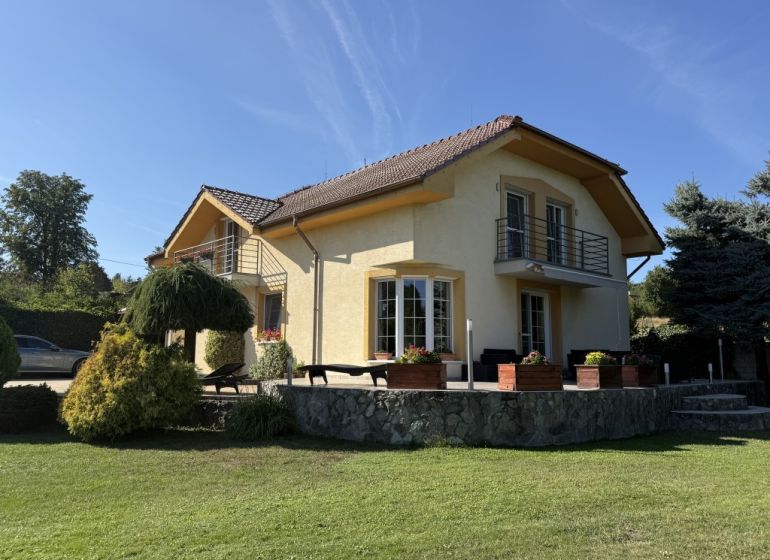 A family house in Zlaté Moravce, surrounded by greenery, with a stone terrace and a balcony.