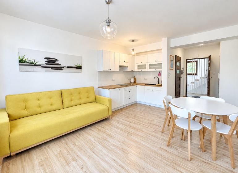 Living room in a studio apartment with wood-patterned flooring and a yellow sofa.