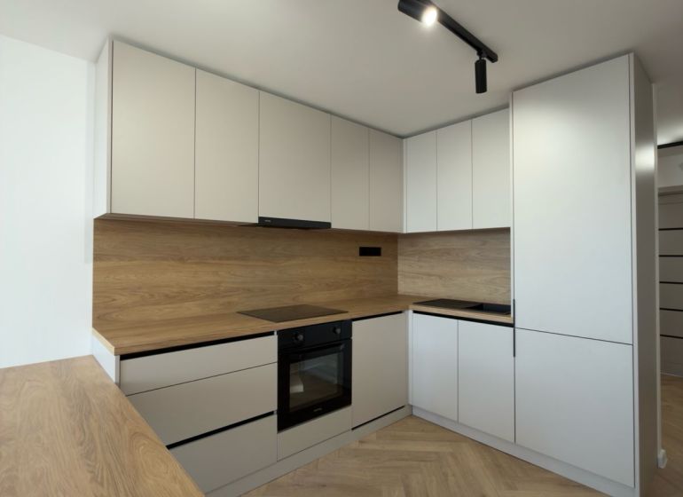 A kitchen in a 4-room apartment with a wooden decor floor and modern cabinets.