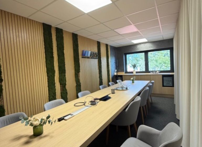 Conference room in a building with a wood-patterned floor and a long table.