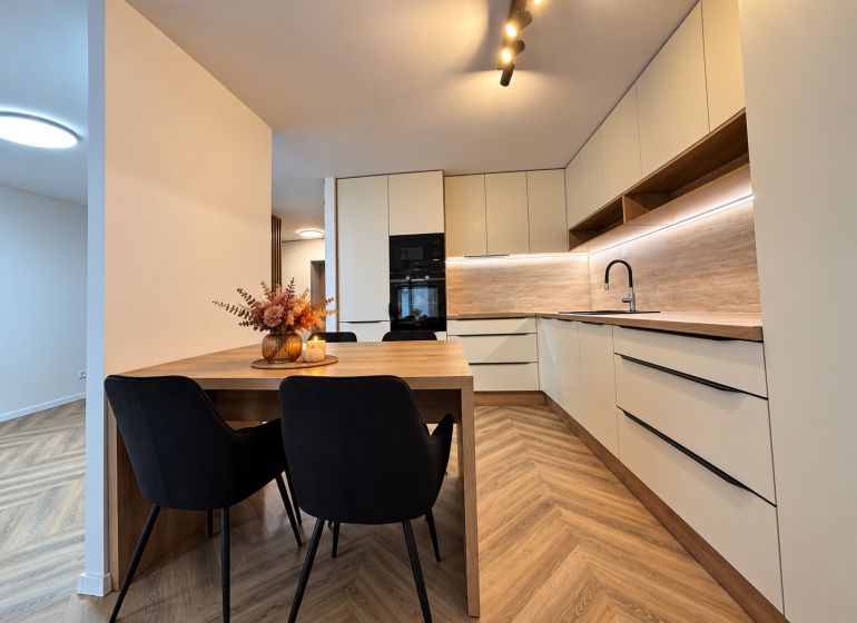 A kitchen in a 3-room apartment with pleasant lighting and a wooden decor floor.