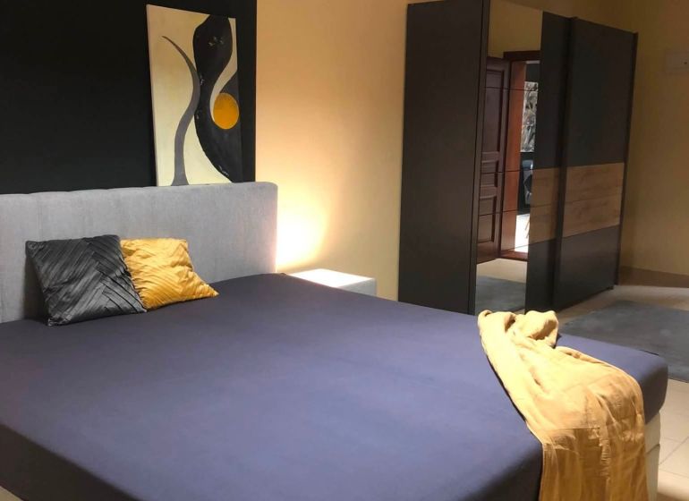 A bedroom with a double bed, a wardrobe, and abstract art in a 2-room apartment.