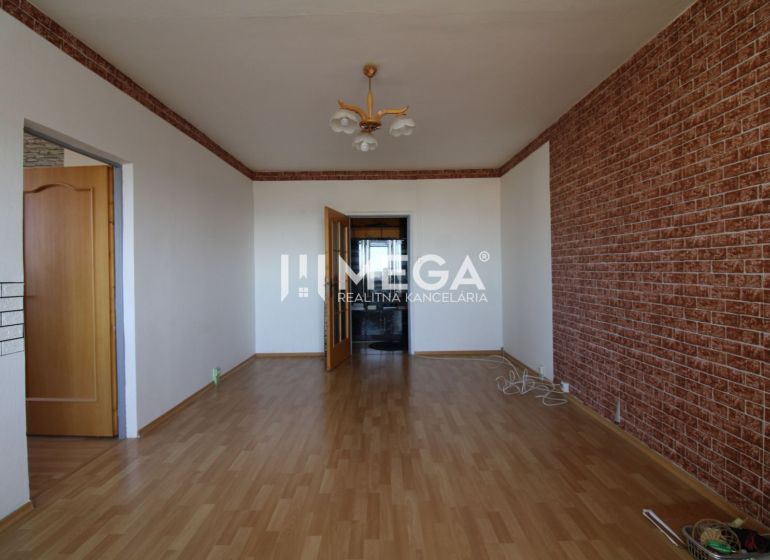 A room in a 3-room apartment with a wooden decor floor and a brick pattern on the wall.