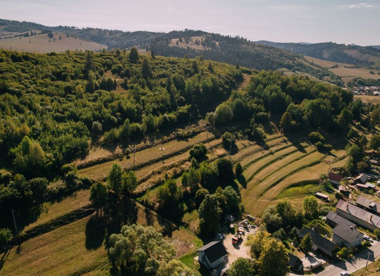 Aerial view of green hills and houses on Školská Street in Čierny Balog.