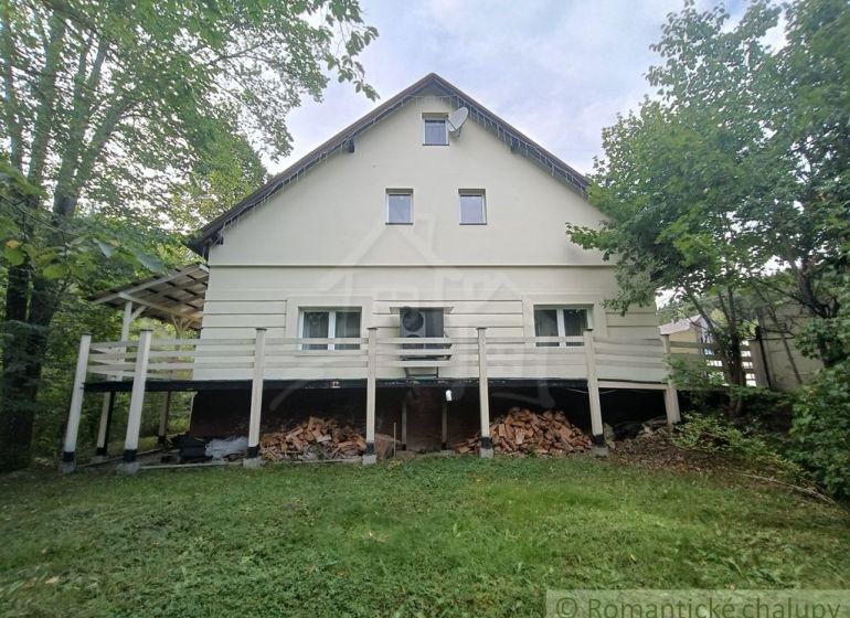 A family house in Staškov, surrounded by greenery, with wood stored under the terrace.