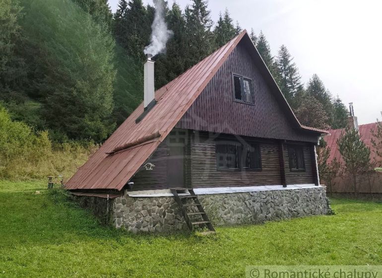 A cottage in Rajecká Lesná surrounded by forest with smoke coming from the chimney.