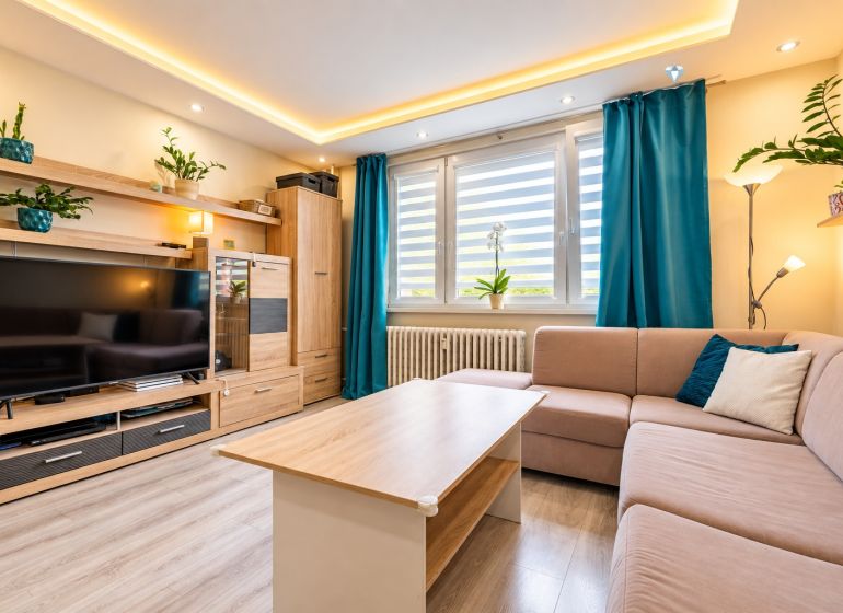 Living room with a sofa set, television, and wooden decor flooring in a 3-room apartment.