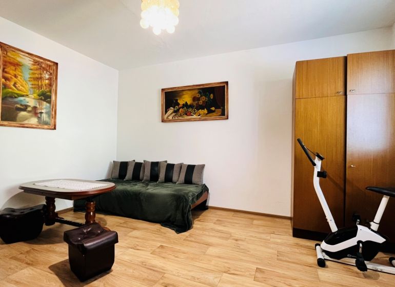 A room in a 3-room apartment with a sofa, a table, and a floor with a wooden decor.
