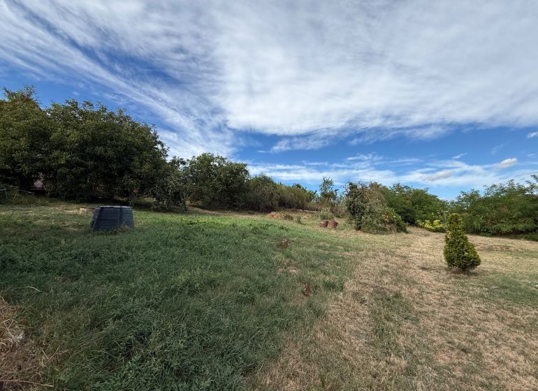 Plots - housing in Krušovce with grassy area, trees, and blue sky.