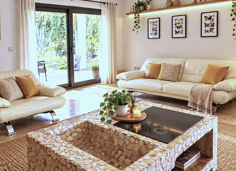 Living room in a family house with light sofas, plants, and large windows.