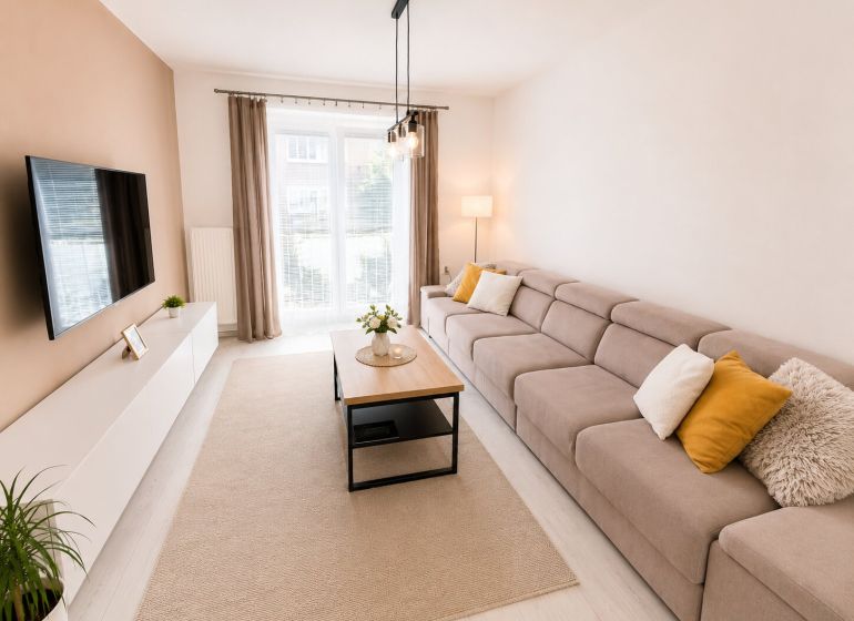 Bright living room in a 2-room apartment with a comfortable couch and windows.