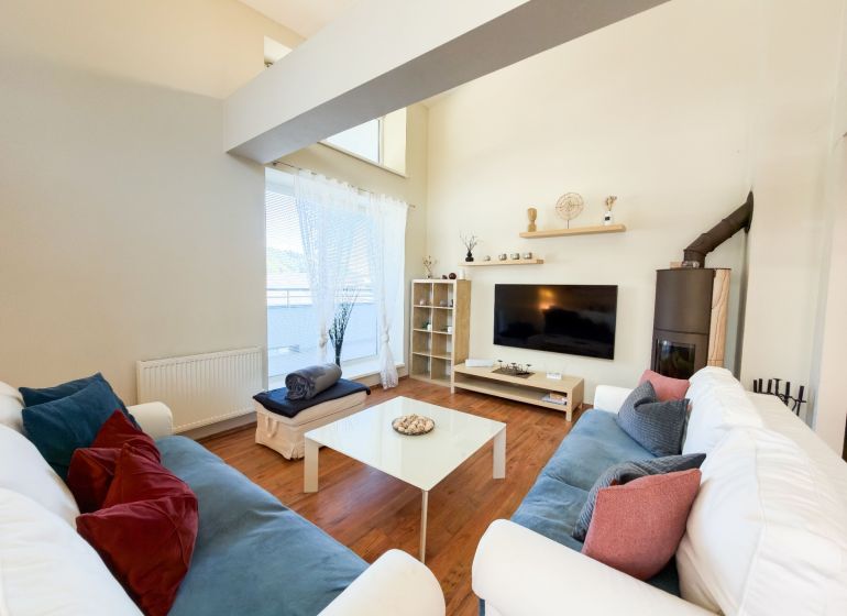 Living room in a three-room apartment with a wooden decor floor, comfortable couches, television.