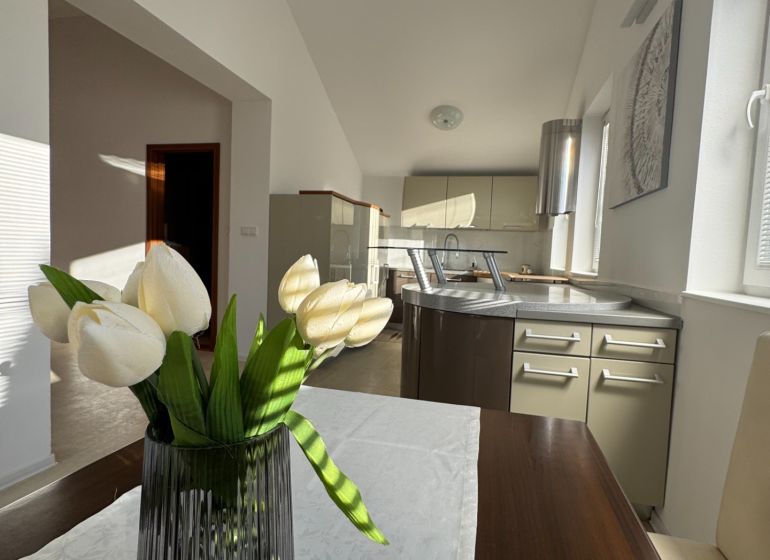 A kitchen in a family house with a decorative vase and white flowers on the table.