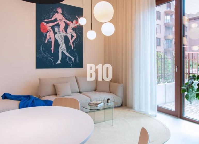 Living area with white furniture, a round table, and art in a 2-room apartment.
