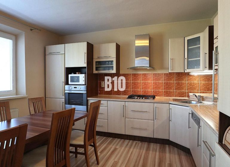 A kitchen with a corner unit, a wooden table, and a floor with a wooden decor.