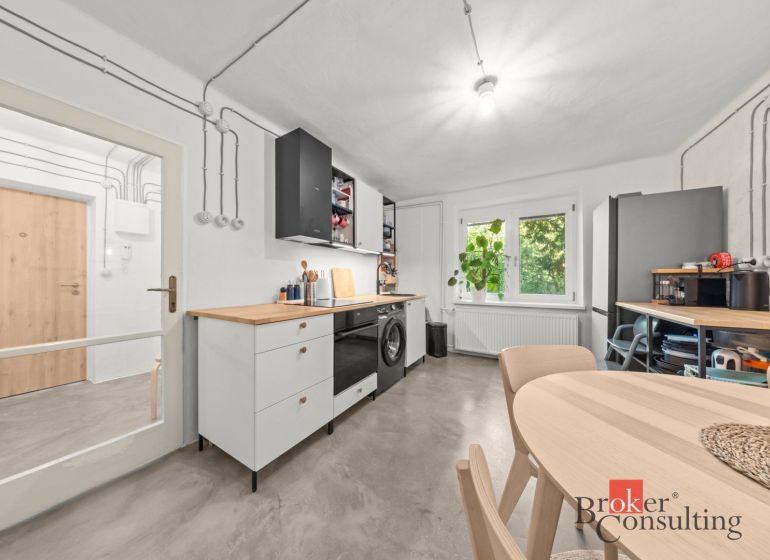 A kitchen in a 2-room apartment with a wooden decor floor and a spacious table.