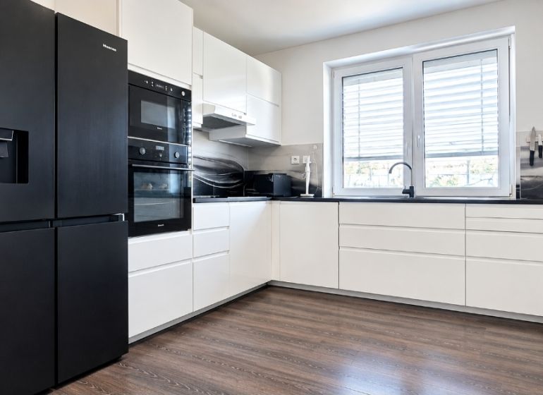 A kitchen unit with black appliances and a wooden decor floor in a family house.