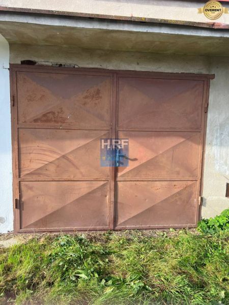 Rusty metal garage doors on Veterná Street in Holíč, surrounded by grass.