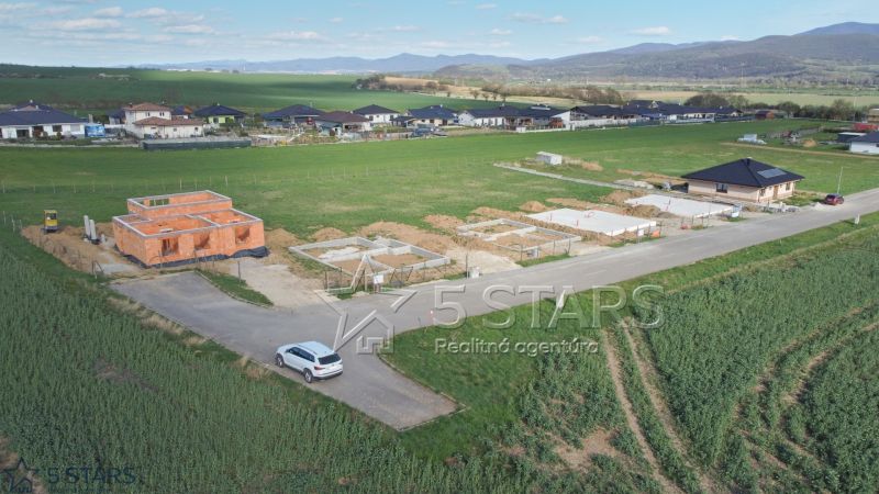 Construction of family houses in Trenčín surrounded by green countryside and other houses.