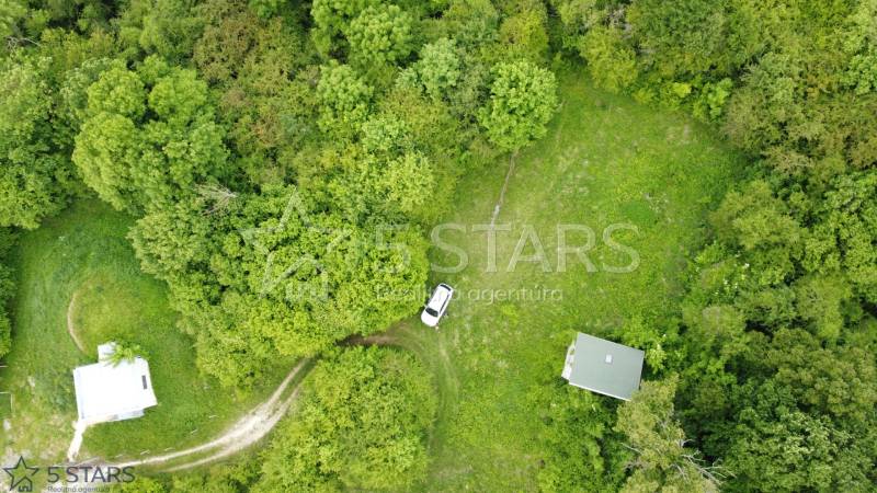 Aerial view of recreational plots in Kostolná-Záriečie surrounded by dense forest and meadow.