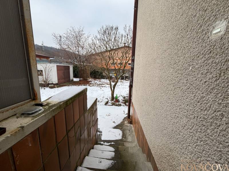 Snowy steps leading to a courtyard with trees in Trenčín on Zamarovce Street.