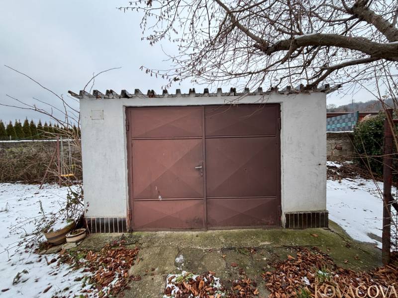A garage in Zamarovce, Trenčín with an old brown metal entrance and a snow cover.