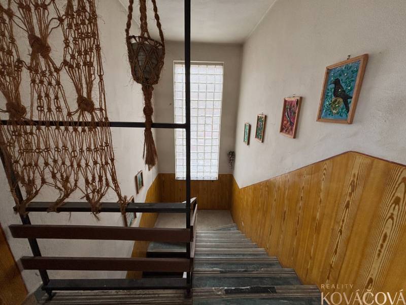 A staircase in a 4-room apartment with wooden paneling, hanging decorations, and paintings.